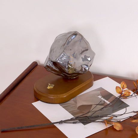 Smoke gray glass ice form unlit on the dark wood plinth