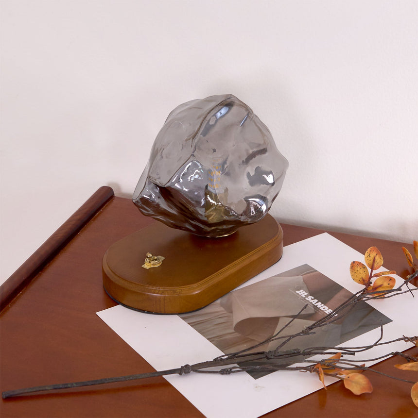 Smoke gray glass ice form unlit on the dark wood plinth