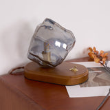 Smoke gray glass ice form unlit on a desk beside dried leaves