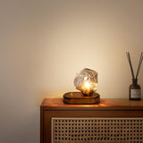 Glass ice form lamp lit on a cabinet beside a reed diffuser