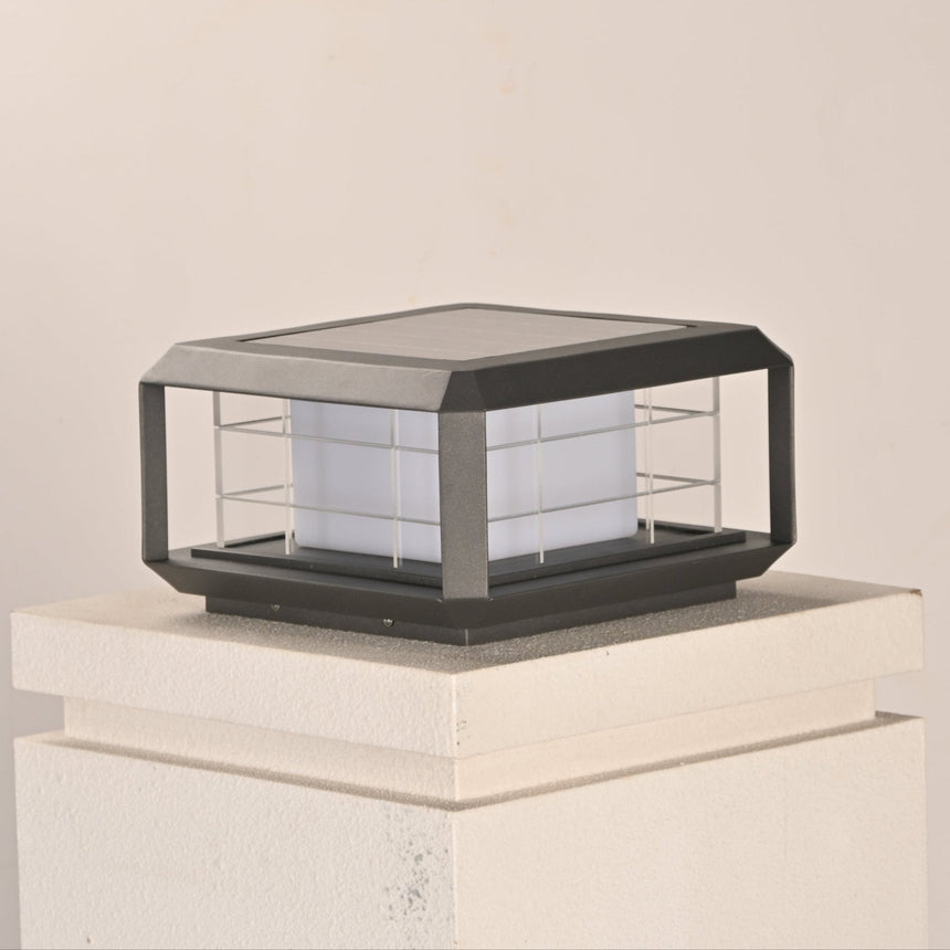 The lantern unlit on a white pillar cap seen from a low garden angle