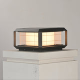 The lantern lit on a white rendered pillar cap above a stepped collar