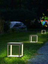 Frames lit on a lawn at night with trees and a parked car behind