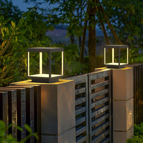 The frame lit on a pillar beside a slatted gate with trees behind