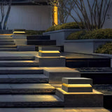 Caps glowing on pillars above dark stone steps in an evening garden