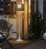 The lamp lit outside glass doors beside potted planting and a chair