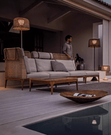 The lamp lit on a deck beside a pool with a long sofa and a low table