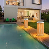 Two lit at the edge of a lit pool with a modern house behind them