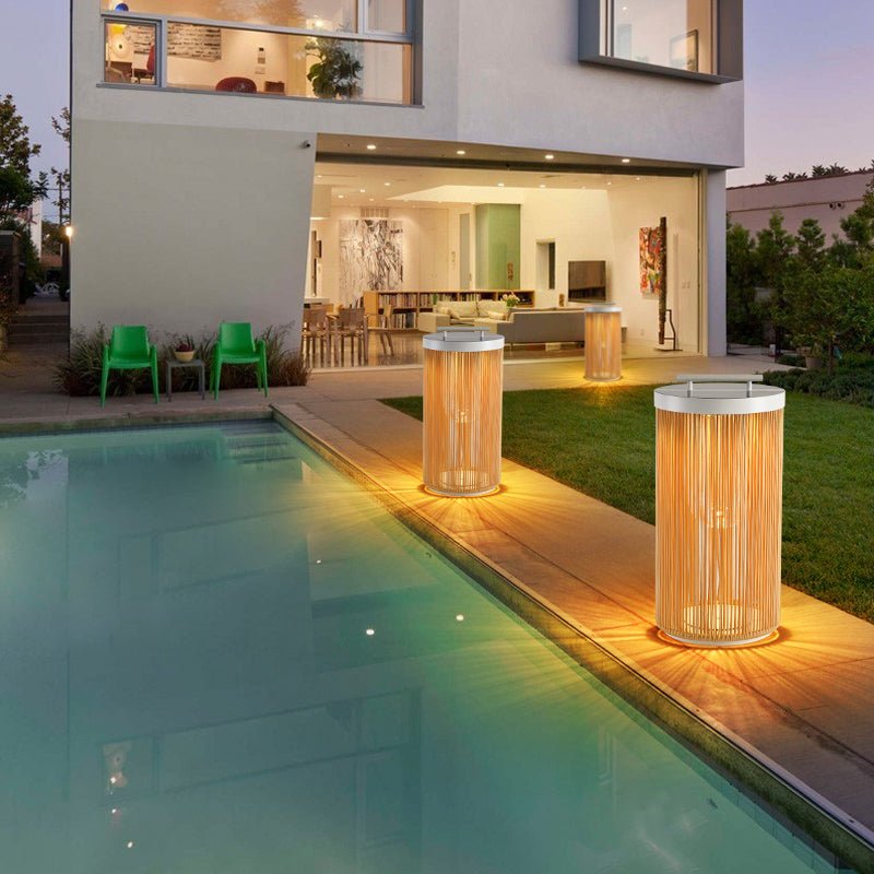 Two lit at the edge of a lit pool with a modern house behind them