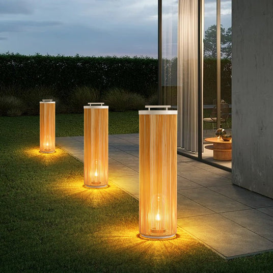 Three sizes lit on a lawn beside a paved walk and a lit house