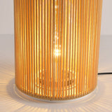 The lit bulb seen through the vertical rattan strands of the column
