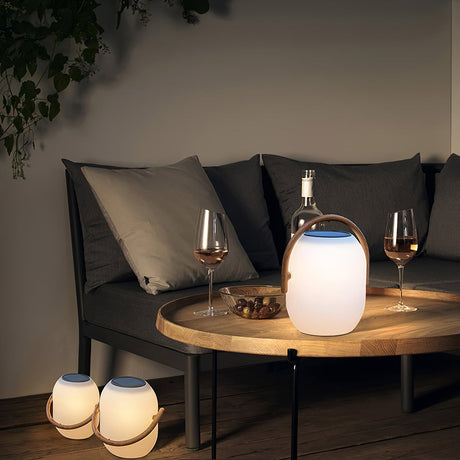 Two lamps lit on a low round table with wine glasses on a terrace