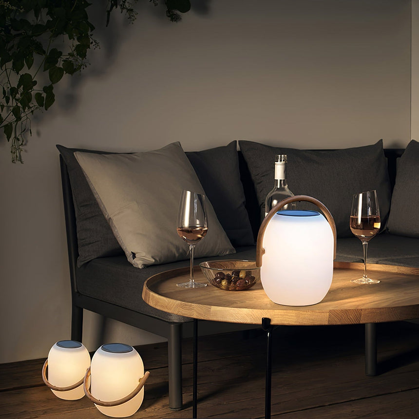 Two lamps lit on a low round table with wine glasses on a terrace