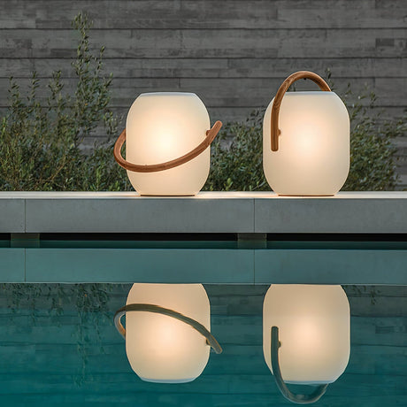 Two lamps lit on a pool edge at dusk with their reflection in the water