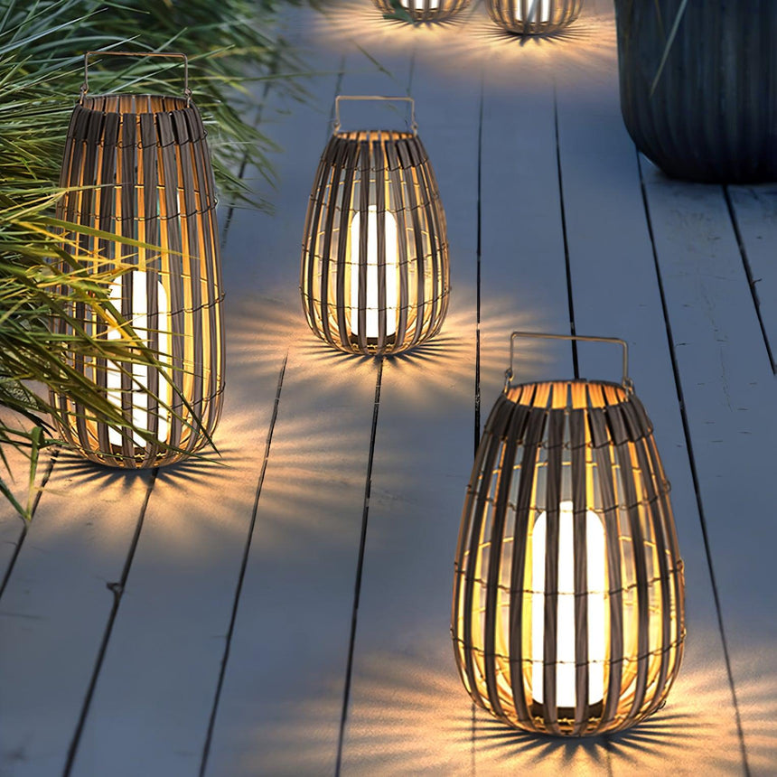 A row of lanterns lit along a timber deck with grasses at the edge