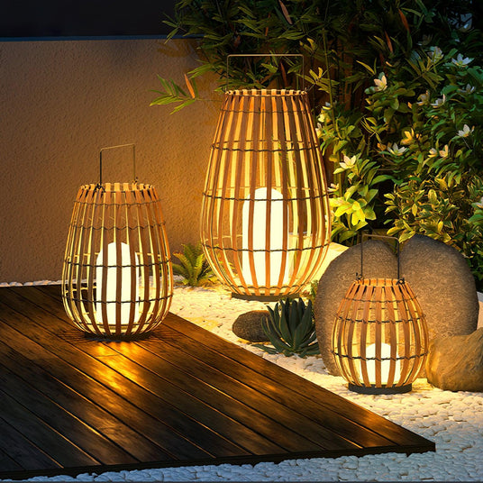 Lanterns lit on a timber deck beside succulents and pale garden stones