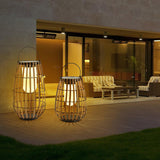Two lanterns lit on a lawn outside a modern house with a lit terrace