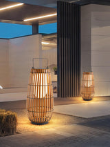 Two lanterns lit at a paved entrance beside a planted border at night