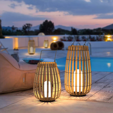 Three lanterns lit on a white pool terrace with the sea behind at dusk