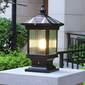 The lantern lit on a stone pillar beside a metal railing at nightfall