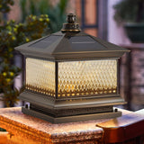 Lit lantern on a brick pillar against a warm painted garden wall