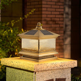 Copper toned lantern lit on a cut stone pillar beside a garden path