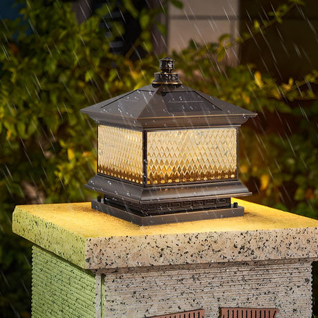The lantern glowing on a stone pillar with grass and shrubs around it