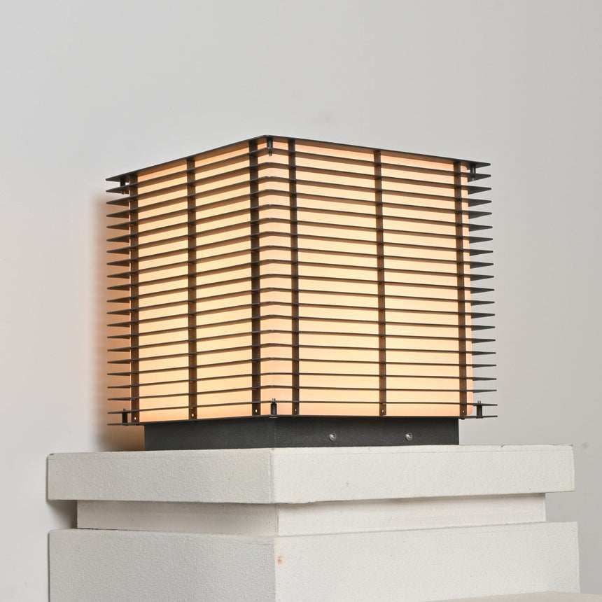 The cube lit warm on a stone plinth with the slats reading as lines