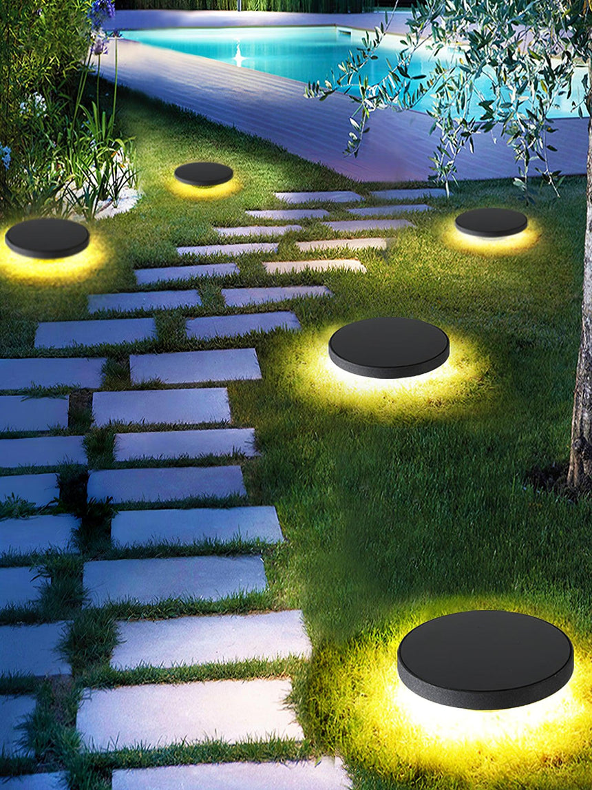Several lit beside stepping stones leading past a lit swimming pool