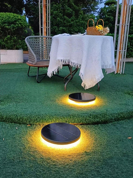 Two lit on grass beside a small table and a woven garden chair