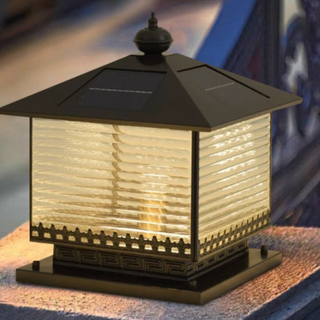 Warm light from the lantern on a pillar with a garden wall behind