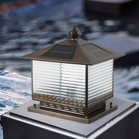The lantern lit on a stone plinth beside still water at the end of day