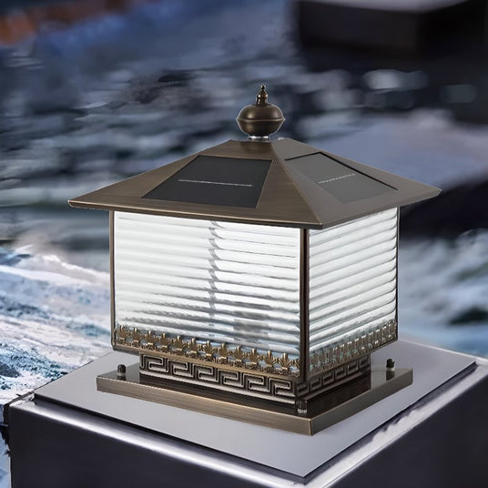 The lantern lit on a stone plinth beside still water at the end of day