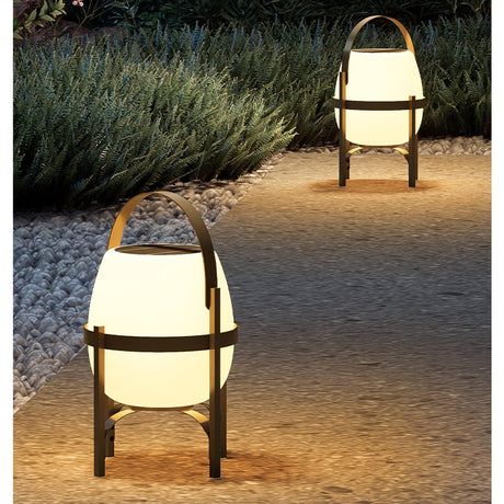 The lamp lit on a gravel path with lavender planting beside it at night