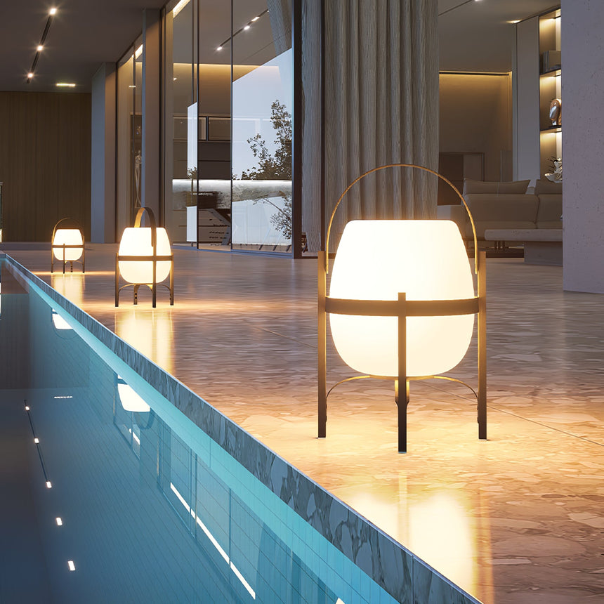 A run of lamps lit along the edge of a lit pool beside a terrace