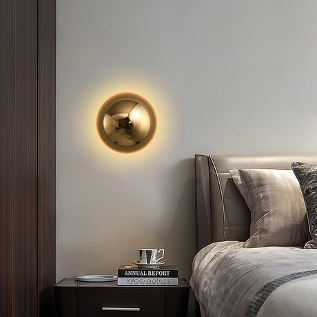 The gold sphere lit above a nightstand with books beside a bed