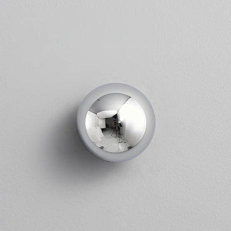 The chrome sphere on a pale wall, reflecting the room