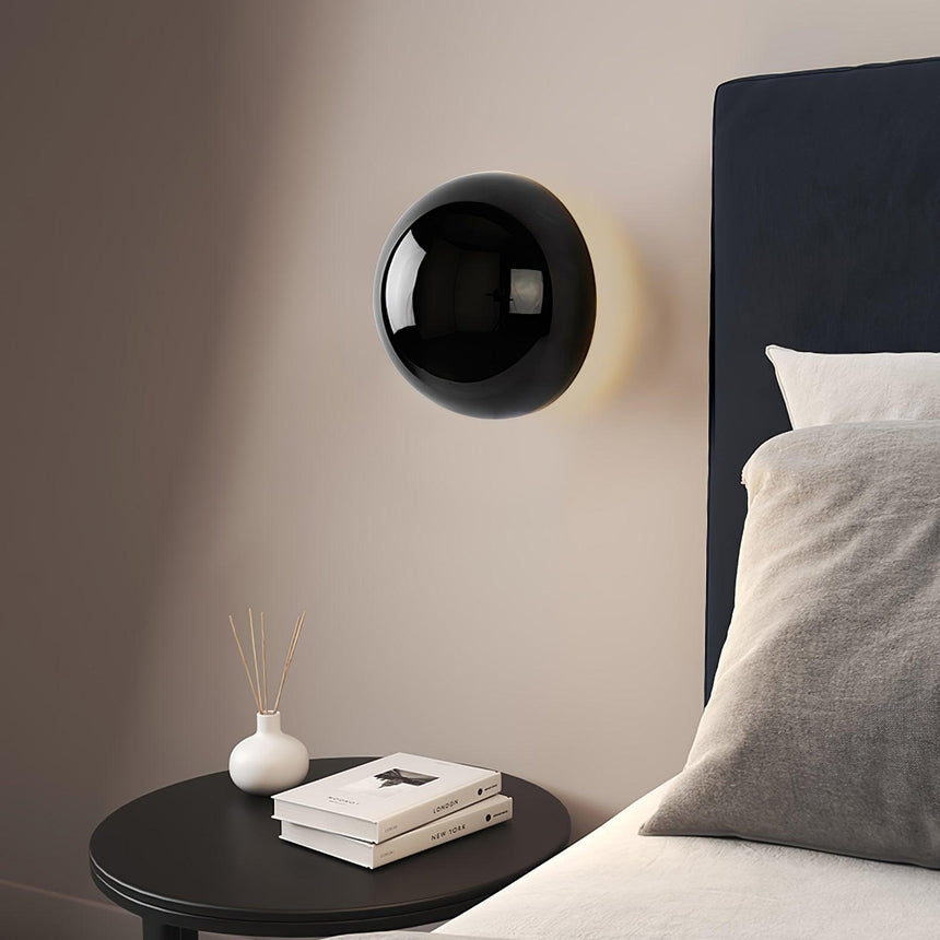 The black sphere beside a dark headboard above a round side table