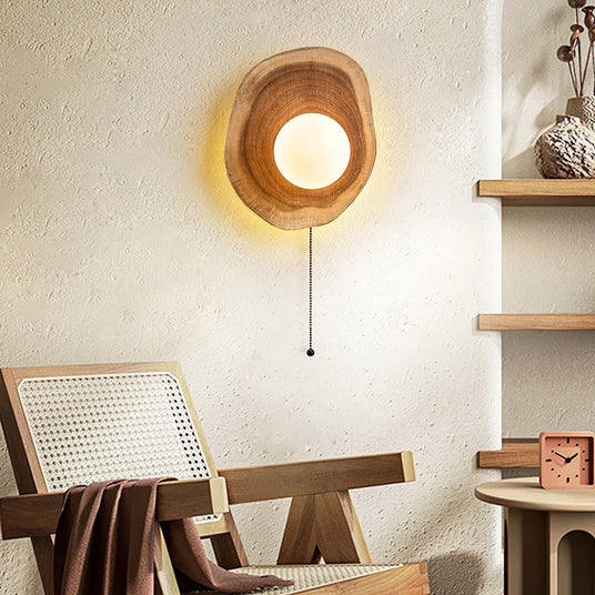 Sconce lit on a plaster wall above a cane chair and a low wood stool