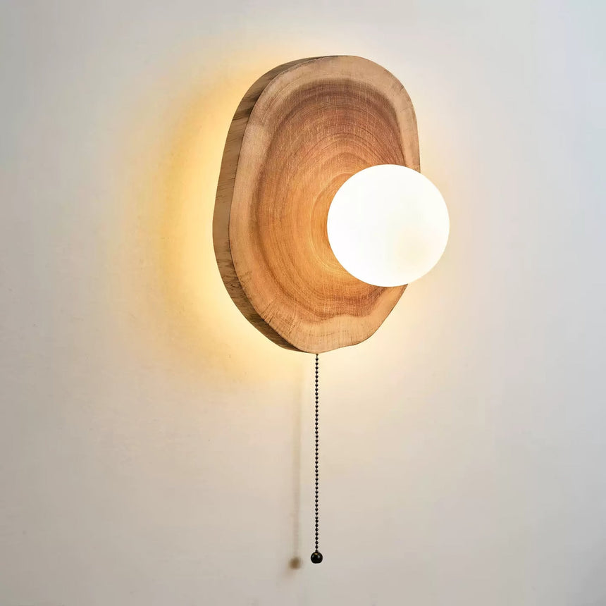 The sphere lit inside the slab, warm light washing the wall behind it