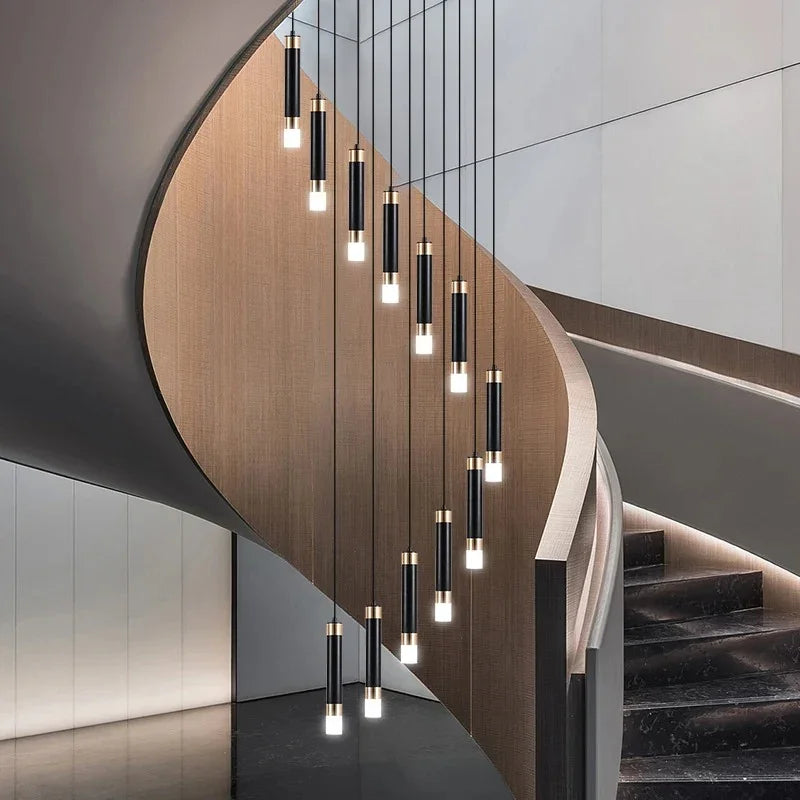 Cylinders spiralling beside a wooden staircase with a dark handrail