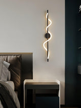 The lit spiral beside a bed with a dark headboard and a small table