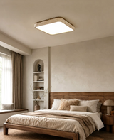Square travertine ceiling light lit above a bed with a striped throw and an arched niche