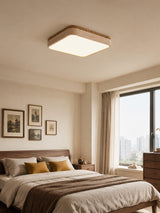 Square travertine ceiling light in a bedroom with framed photographs and a city window