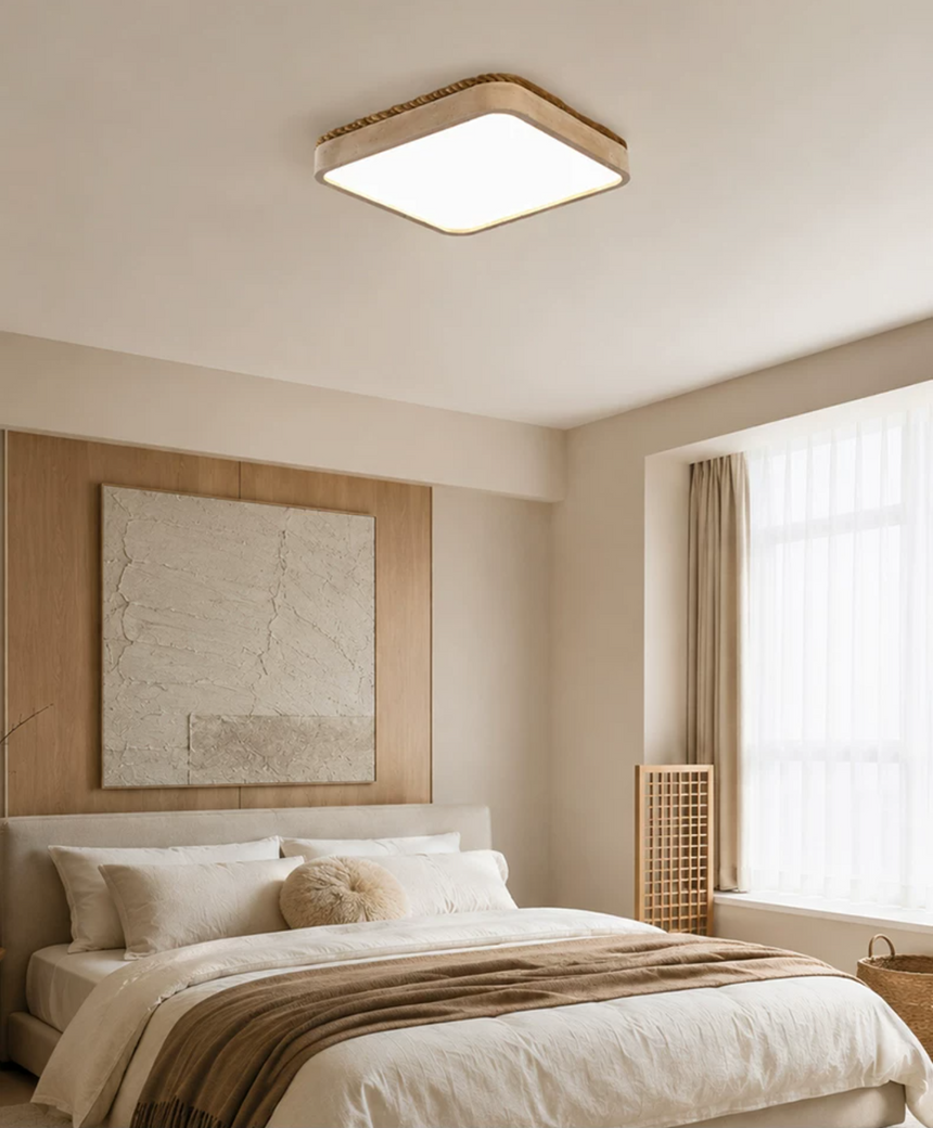 Square travertine ceiling light above a bed with a woven stool and a wall map