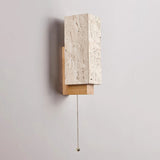 The pull chain hanging from under the wood bracket beside the stone block