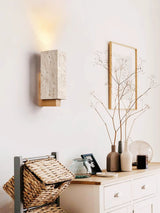 Sconce lit beside a framed print above a console with a woven basket