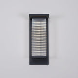 Front view of the lantern on a gray wall with the ribbed panel lit