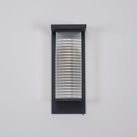 Front view of the lantern on a gray wall with the ribbed panel lit