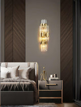 The sconce lit on a wood herringbone wall above a bed with gray pillows